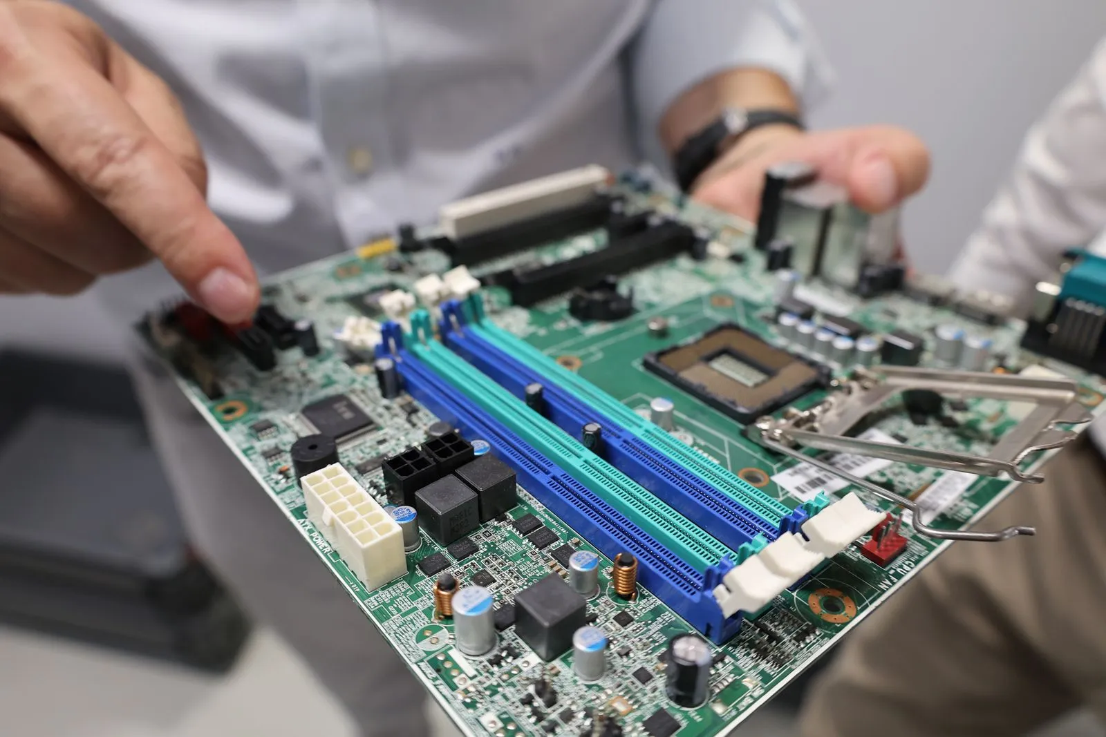 Close-up of a technician handling a computer motherboard, emphasizing technology and electronics.